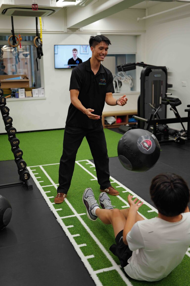 Coach demonstrating a medicine ball exercise on the turf