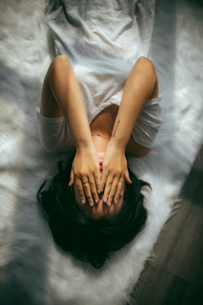 Person sitting on a bed holding their knees, illustrating different types of headaches
