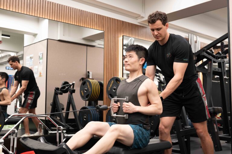 Coach supervising a client performing barbell rows in the gym